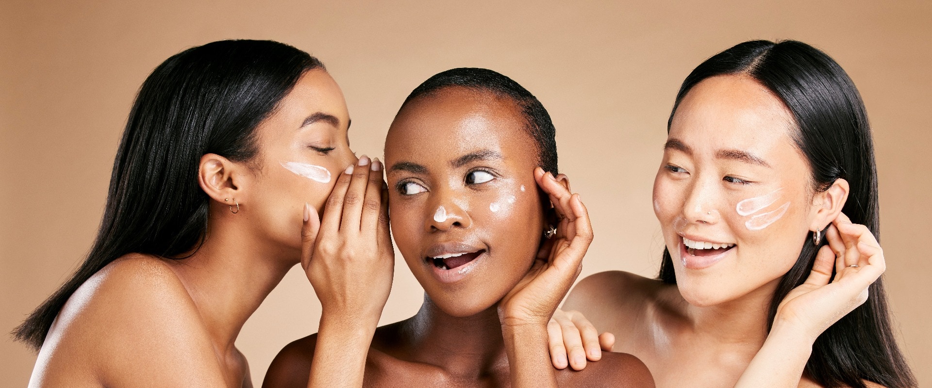 Beauty secret, skincare cream and diversity women friends whisper about inclusion advertising in studio. Asian and black people talk about wow skin glow, spa facial and face with dermatology product